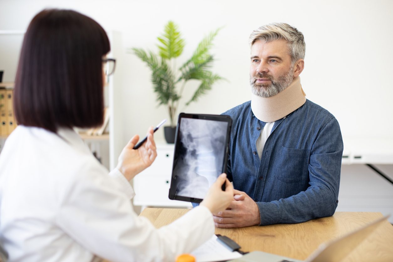 Doctor reviewing imaging results with patient using cervical soft collar