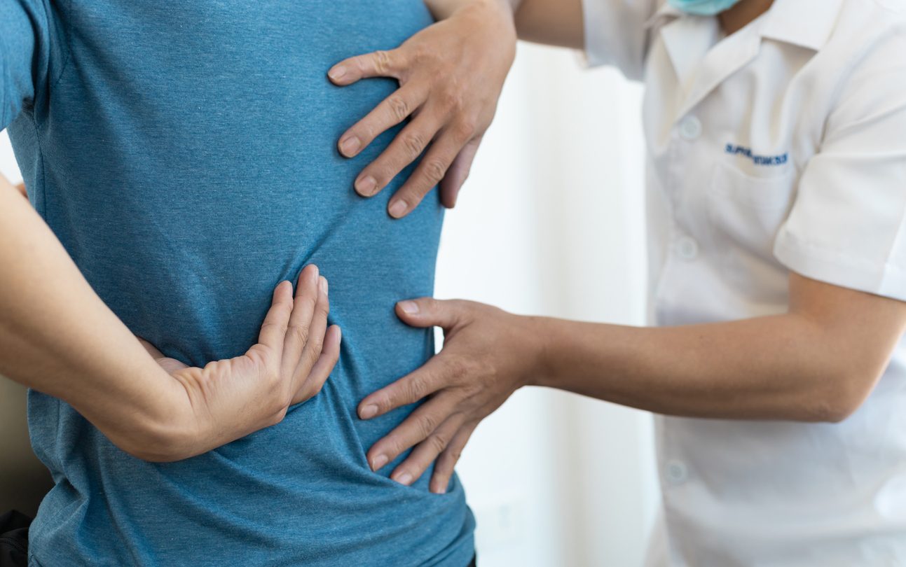 Physician consulting with patient on back pain caused by scoliosis