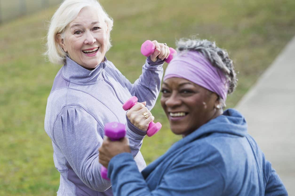Two people walking in a park while holding hand weights
