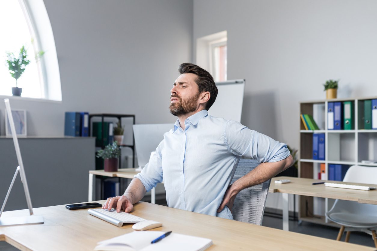 Person at work feeling lower back pain in need of lumbar disc microsurgery