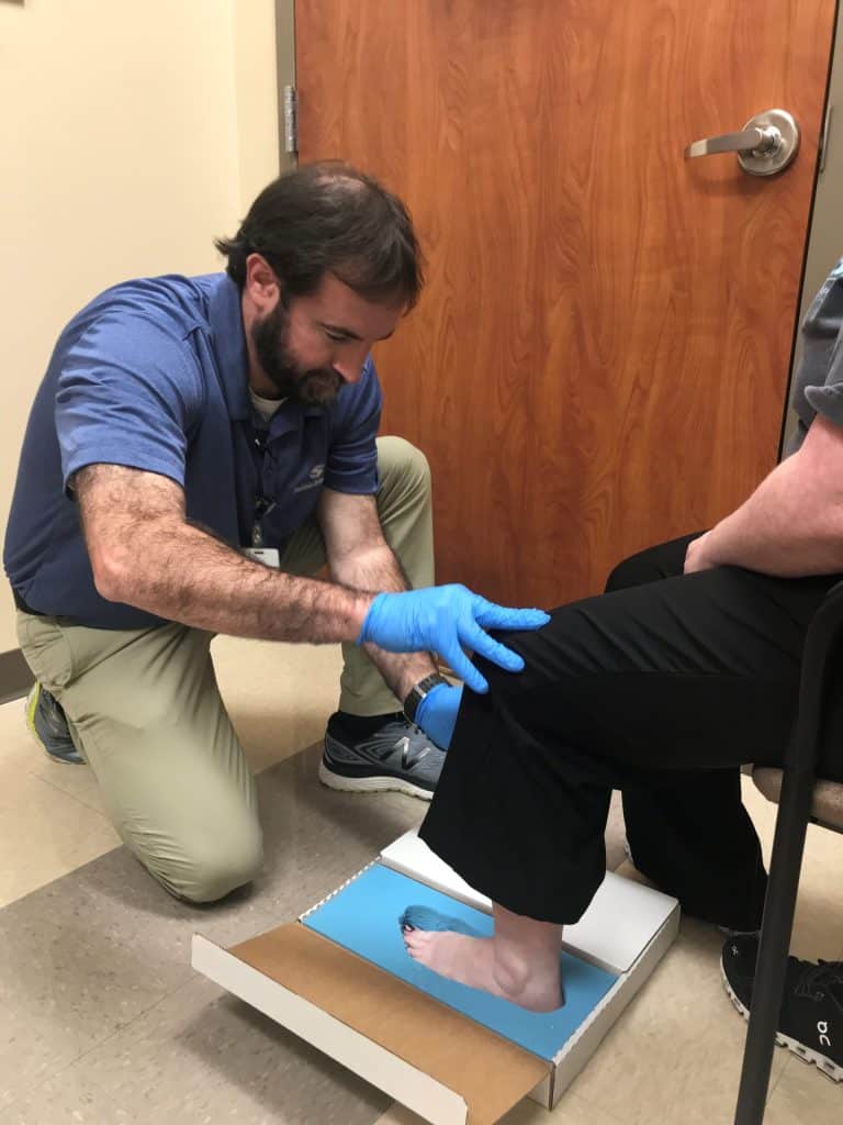 Southlake Orthopaedics’ orthotics doctor assisting patient with an imprint of foot for orthotic