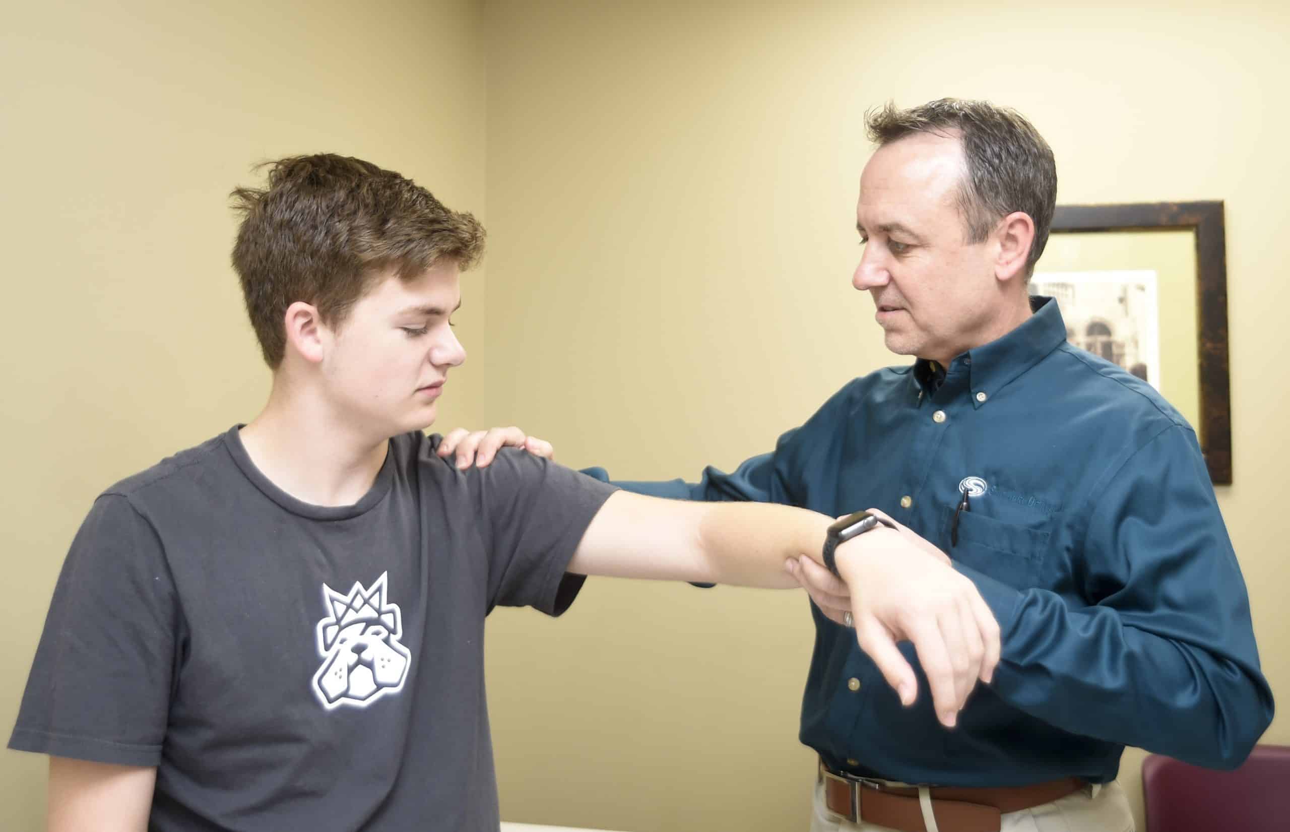 Southlake Orthopaedics’ Dr. Michael T. Ellerbusch, MD providing shoulder care by examining a male patient’s dislocated shoulder