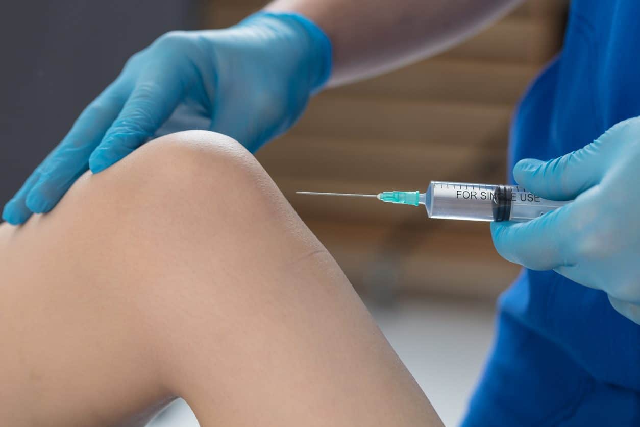 Doctor administering a steroid injection in a patient’s knee for arthritis