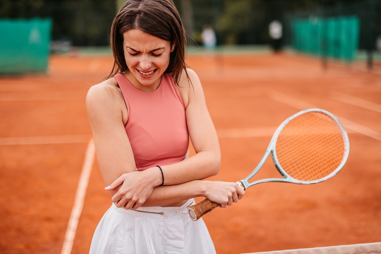 Tennis player grabbing elbow in pain