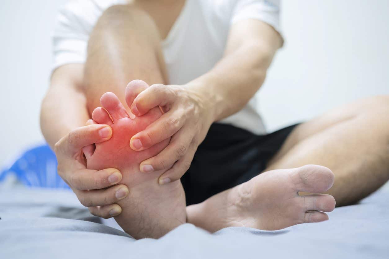 Patient clutching foot outlined in red, indicating swelling