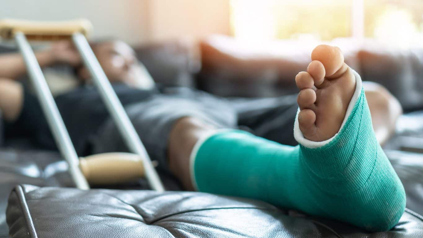 Patient on couch with crutches and cast on foot