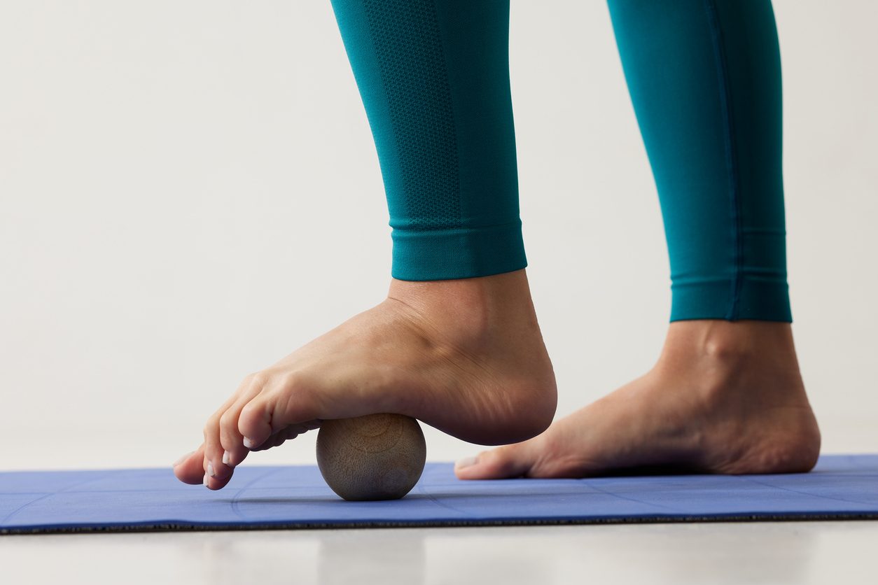 Patient standing on small exercise ball, extending arch of foot