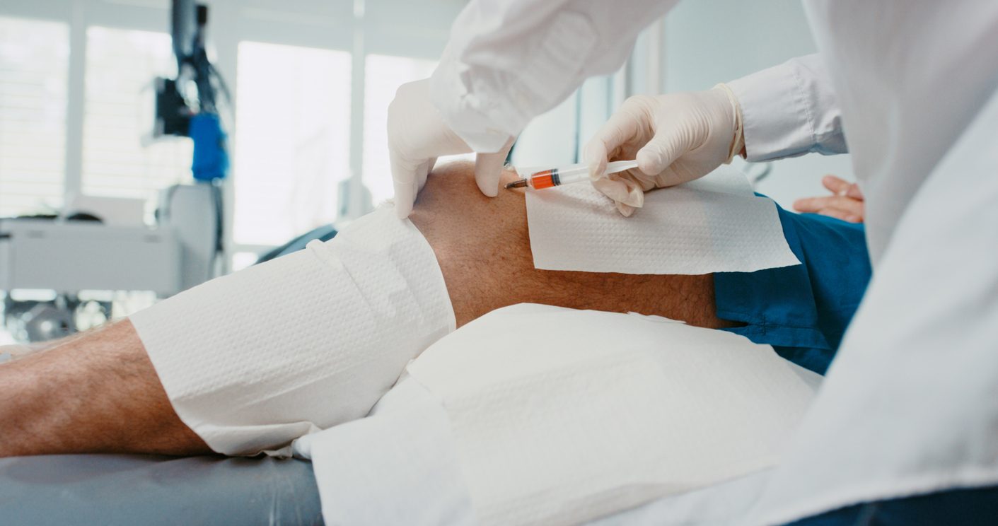 Orthopedic specialist performs injection into patient’s knee