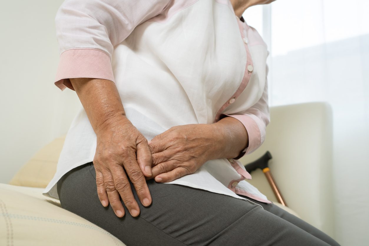 Patient clutching hip in pain while sitting down