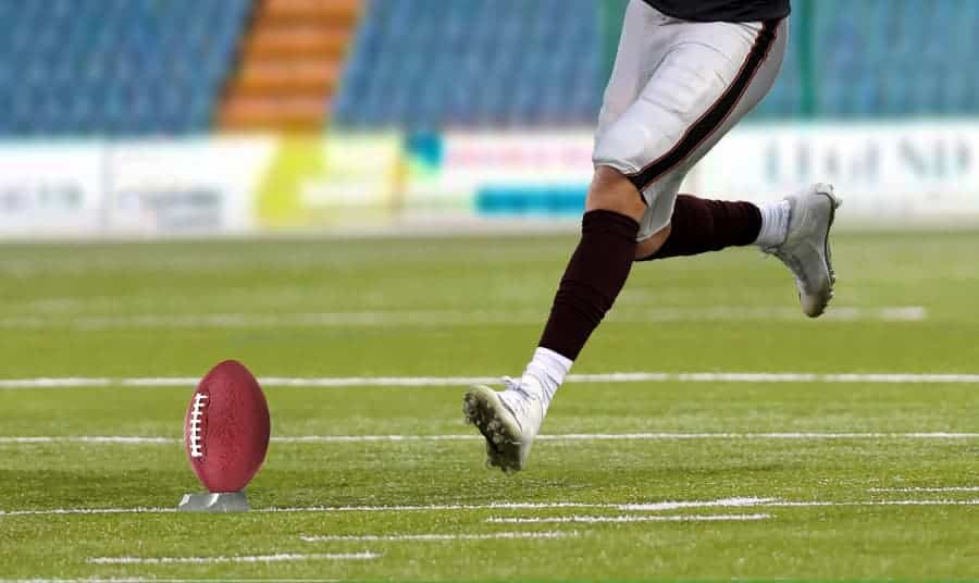 Football player about to kick football for field goal
